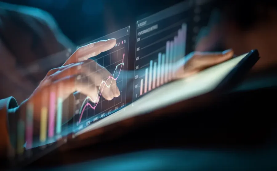 Hands working on a screen with glowing charts