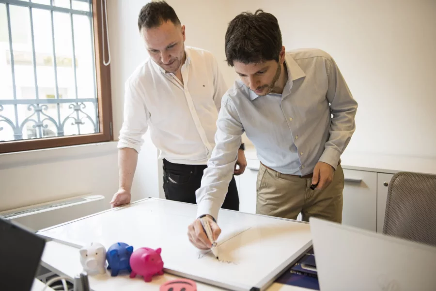 Two colleagues sketching an idea on a whiteboard in the office
